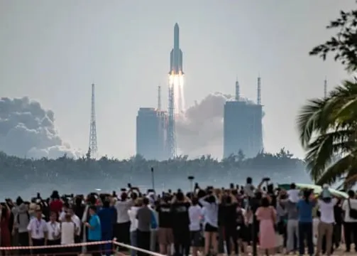 Spectators watching a Long March rocket lift off from a coastal launch site
